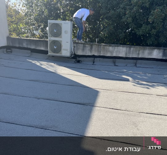 אדם על גג עם יריעות איטום ואיטום סביב מזגן